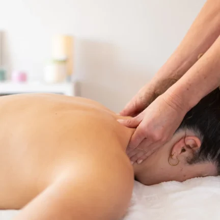 Side view of crop female massage therapist rubbing neck of patient lying on treatment bed during appointmentat the  spa