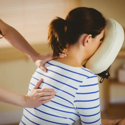 Young woman getting massage in chair in therapy room