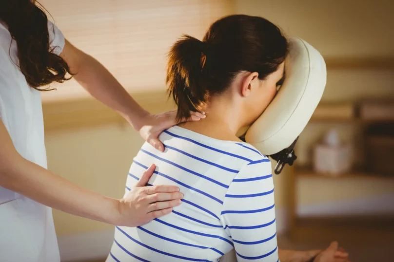 Young woman getting massage in chair in therapy room