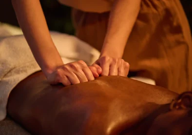 Medium close up of unrecognizable female hand performing deep tissue massage in the back of African American woman