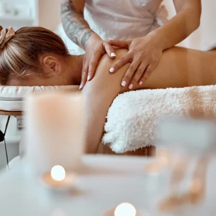 Massage therapist performing Therapeutic Massage procedures to caucasian woman at spa