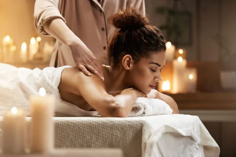 Young tender african girl smiling enjoying massage with closed eyes in spa resort.