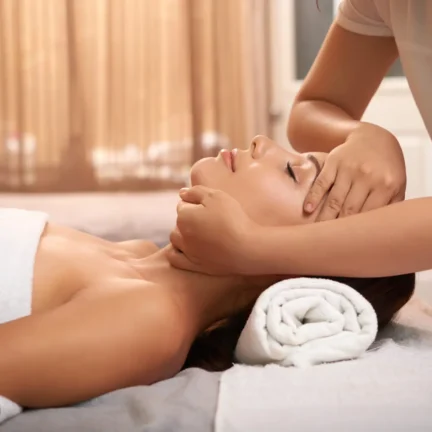 Young woman having myofascial massage on her face while relaxing in spa bed