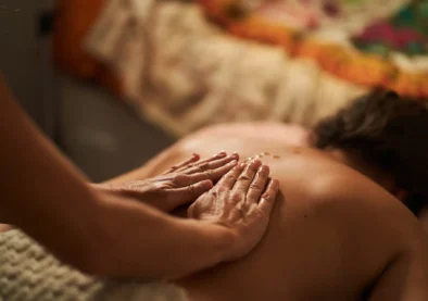 Close-up of masseur's hands applying oil on client's back during a relaxing massage therapy session, promoting wellness and relaxation