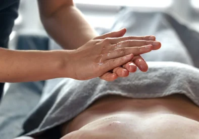 Masseur rubbing aromatic oil in a calm spa atmosphere, preparing client for relaxing body massage.